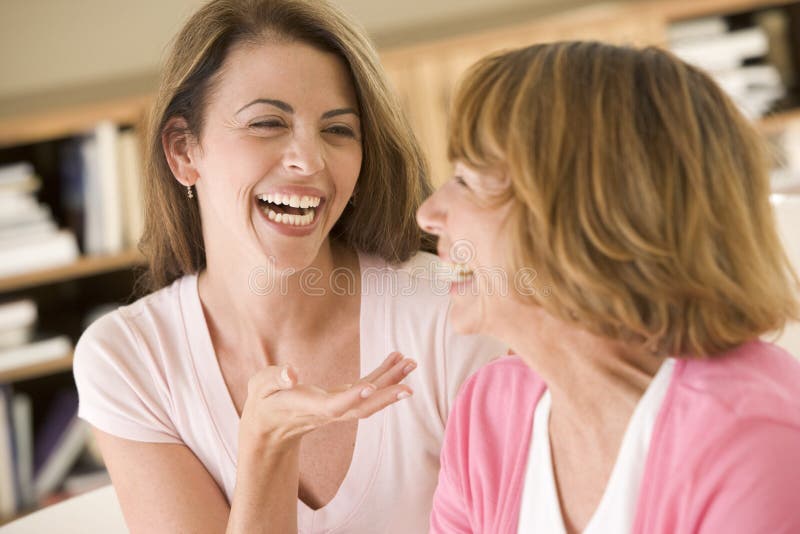 Zwei Frauen, die in der Wohnzimmerunterhaltung und -lachen sitzen
