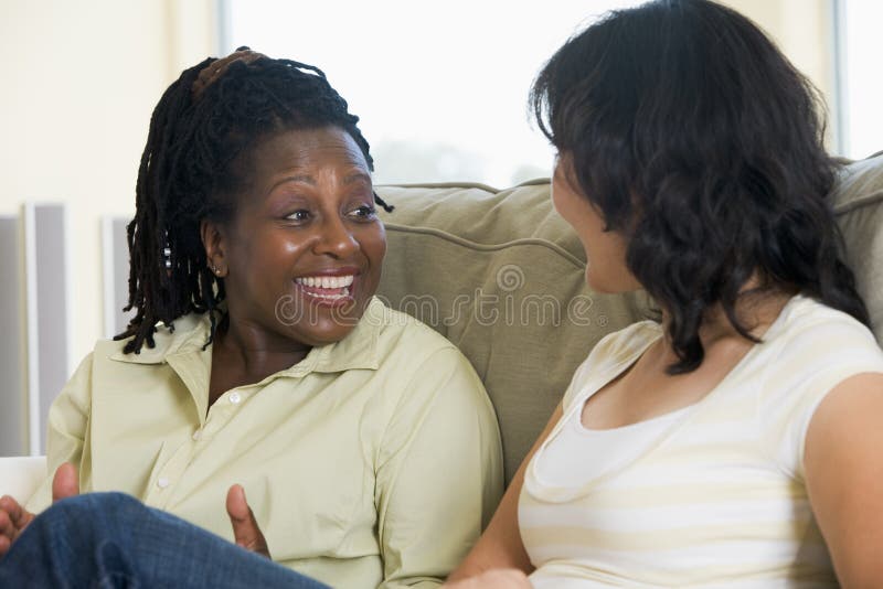 Zwei Frauen, die im Wohnzimmer und im Lächeln sprechen