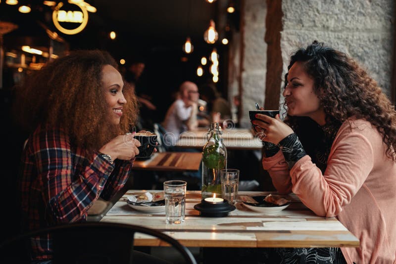 Zwei Frauen, die Kaffee in einem Café sprechen und trinken