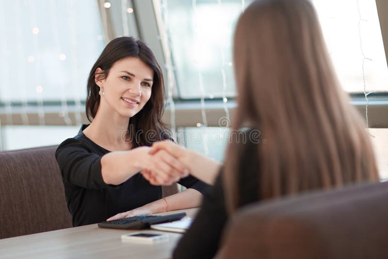 Zwei Geschäftsfrauen, die Hände bei einer informellen Sitzung rütteln stockfoto Zwei Geschäftsfrauen, die Hände bei einer informellen Sitzung rütteln stockfoto