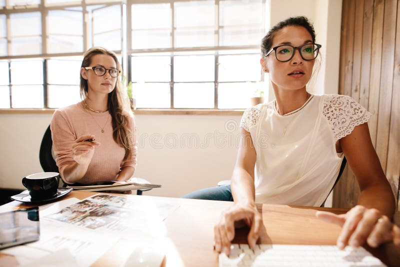 Zwei Geschäftsfrauen, die am Schreibtisch zusammenarbeiten stockbild Zwei Geschäftsfrauen, die am Schreibtisch zusammenarbeiten stockbild