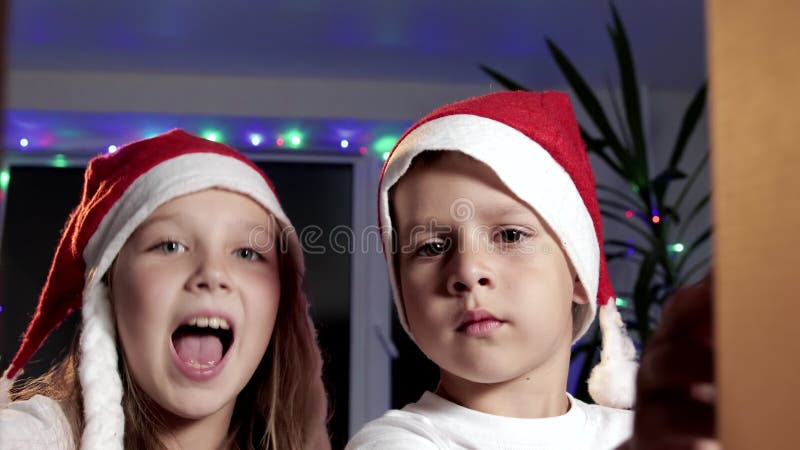 Zwei glückliche Kinder öffnen eine Pappschachtel mit Geschenken Das Konzept der Freude und des Glücks