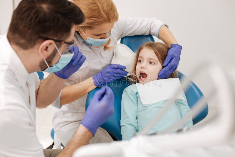 Zwei gut ausgebildete Kollegen, die mit kleinem Mädchen arbeiten lizenzfreies stockbild Zwei gut ausgebildete Kollegen, die mit kleinem Mädchen arbeiten lizenzfreies stockbild