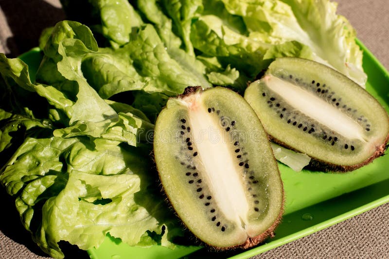 Zwei halbsaftige, reife Kiwi-Früchte, frischer Salat auf dem Teller Grüner Hintergrund Salatblatt Bio-gesunde Lebensmittel Detox- stockfoto
