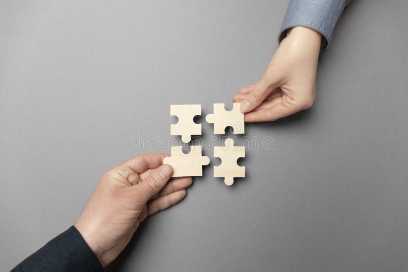 Zwei Hände verbinden Rätsel auf grauem Hintergrund. Unternehmenskooperation. Kollaborateure für Erfolg