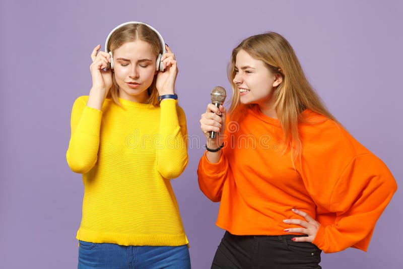 Zwei junge blonde Zwillingsschwestermädchen in der bunten Kleidung hören Musik mit Kopfhörern, singen Lied im lokalisierten Mikro stockbilder Zwei junge blonde Zwillingsschwestermädchen in der bunten Kleidung hören Musik mit Kopfhörern, singen Lied im lokalisierten Mikro stockbilder