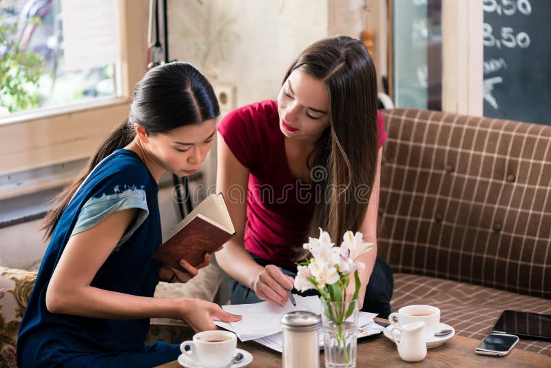 Zwei junge Geschäftsfrauen in einer Kaffeestube stockfotografie Zwei junge Geschäftsfrauen in einer Kaffeestube stockfotografie