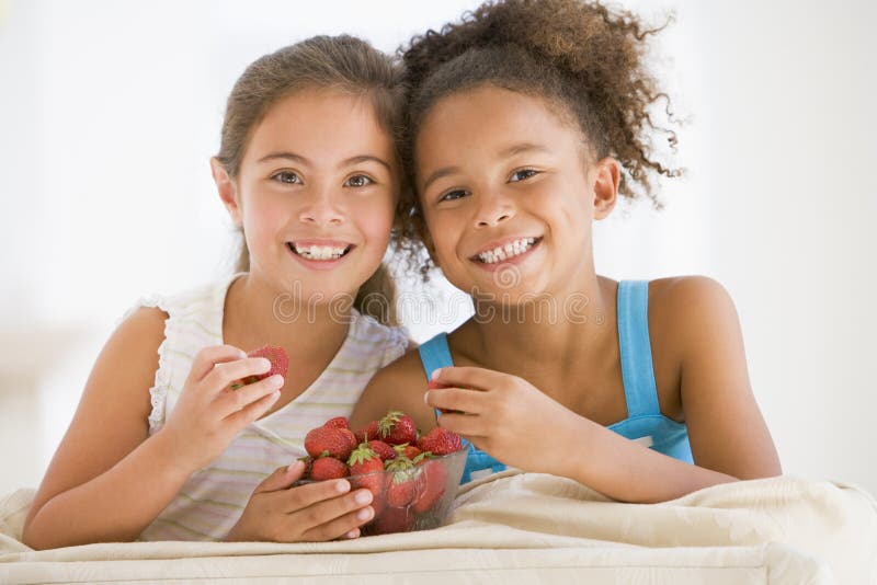 Zwei junge Mädchen, die Erdbeeren essen