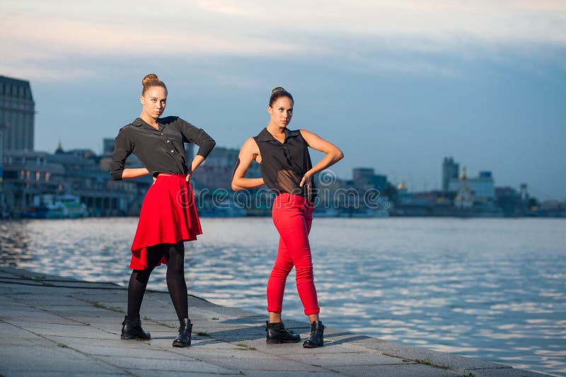 Zwei junge schöne Zwillingsschwestern tanzen waacking Tanz im Stadthintergrund nahe Fluss stockbild Zwei junge schöne Zwillingsschwestern tanzen waacking Tanz im Stadthintergrund nahe Fluss stockbild