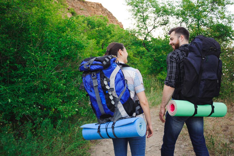Zwei junge Touristen mit Rucksäcken Glückliche Freunde im Hintergrund des Grases und des blauen Himmels, entspannen sich Zeit am stockbilder Zwei junge Touristen mit Rucksäcken Glückliche Freunde im Hintergrund des Grases und des blauen Himmels, entspannen sich Zeit am stockbilder