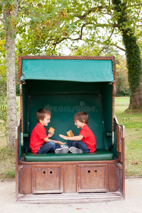 Zwei Kinder, sitzend in einer geschützten Bank, Spielhandklatschen GA lizenzfreies stockbild Zwei Kinder, sitzend in einer geschützten Bank, Spielhandklatschen GA lizenzfreies stockbild