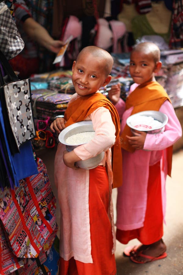 Two child nuns with alms bowls filled with rice collecting the offerings at the market in Myanmar/Burma. Two child nuns with alms bowls filled with rice collecting the offerings at the market in Myanmar/Burma