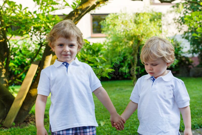 Zwei kleine Geschwisterjungen, die Spaß draußen im Familienblick haben stockfotos Zwei kleine Geschwisterjungen, die Spaß draußen im Familienblick haben stockfotos