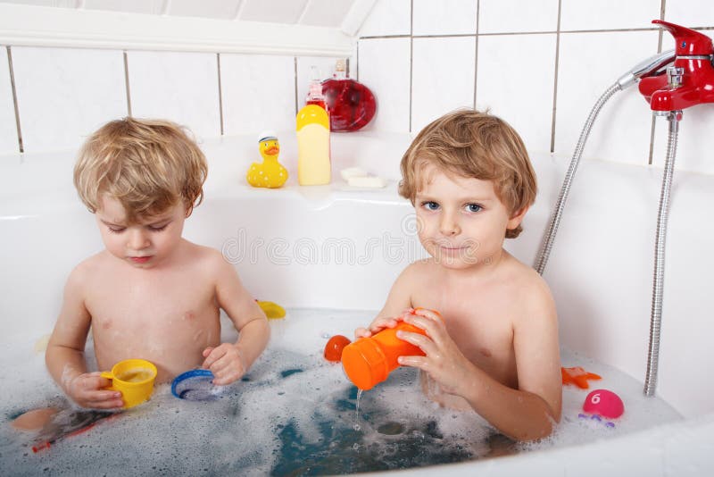 Zwei kleine Zwillingsjungen, die Spaß mit Wasser durch das Nehmen des Bades im Ba haben stockfotografie Zwei kleine Zwillingsjungen, die Spaß mit Wasser durch das Nehmen des Bades im Ba haben stockfotografie