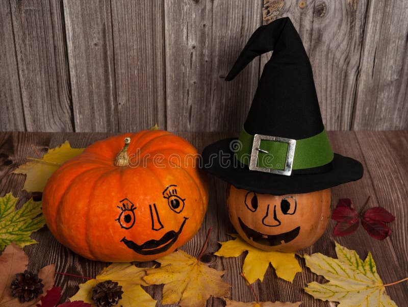Zwei Kürbis mit lustigen bemalten Gesichtern, eine zauberhafte Hexenhut, Zapfen und bunten Herbstblättern auf Holzboden lizenzfreie stockbilder Zwei Kürbis mit lustigen bemalten Gesichtern, eine zauberhafte Hexenhut, Zapfen und bunten Herbstblättern auf Holzboden lizenzfreie stockbilder