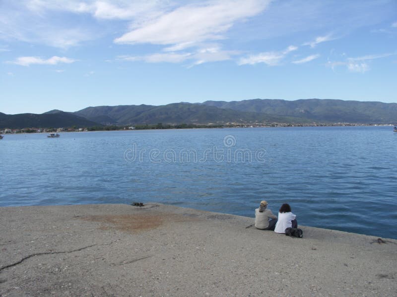 Zwei Leute, die auf dem Dock sitzen stockfoto Zwei Leute, die auf dem Dock sitzen stockfoto