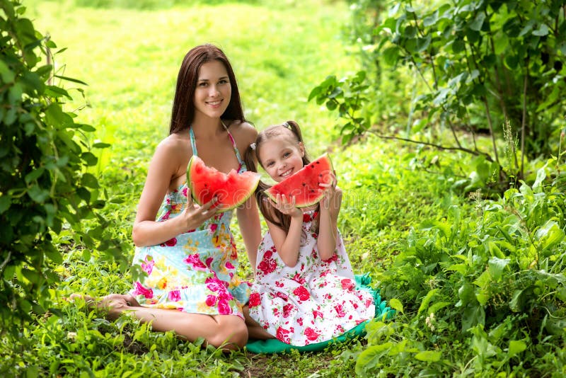 Zwei lächelnde Mädchen isst Scheibe der Wassermelone draußen auf dem Bauernhof lizenzfreie stockbilder Zwei lächelnde Mädchen isst Scheibe der Wassermelone draußen auf dem Bauernhof lizenzfreie stockbilder