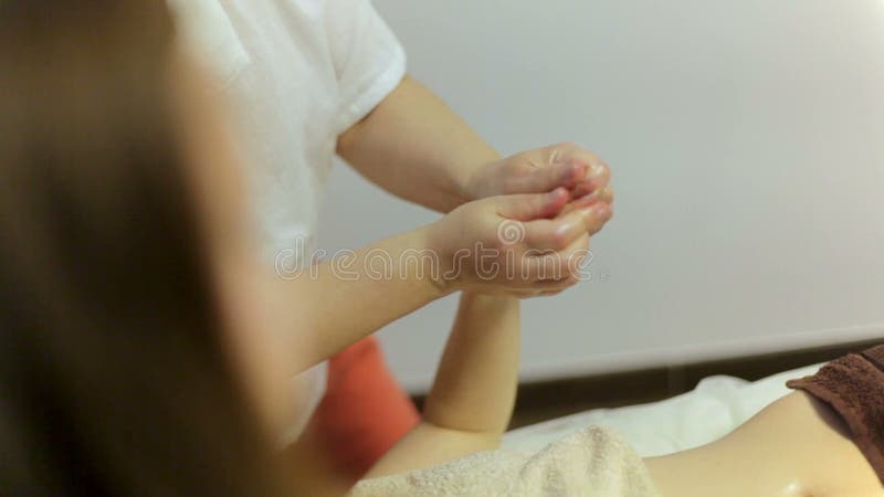 Zwei Masseusen massieren die Hände eines Mädchens in einem Badekurortsalon Ayurvedic-Massage in vier Händen