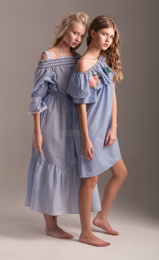 Zwei Modelle in den blauen Kleidern, die auf grauem Hintergrund aufwerfen lizenzfreies stockfoto Zwei Modelle in den blauen Kleidern, die auf grauem Hintergrund aufwerfen lizenzfreies stockfoto