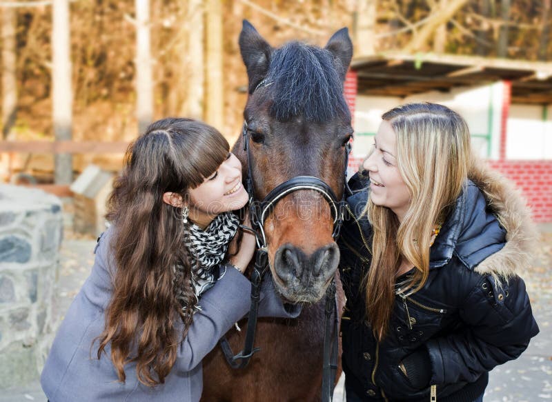 Zwei Mädchen, die ein Pferd anhalten lizenzfreie stockfotos Zwei Mädchen, die ein Pferd anhalten lizenzfreie stockfotos