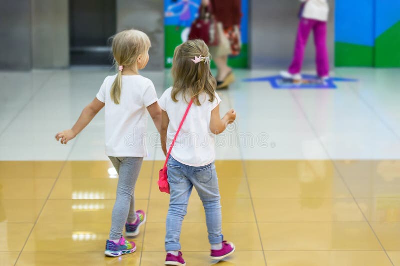 Zwei nette blonde kleine Mädchen, die zusammen in Mall gehen Paare Kinderfreundhändchenhalten während des Wegs Kleinkindfreundsch lizenzfreies stockfoto Zwei nette blonde kleine Mädchen, die zusammen in Mall gehen Paare Kinderfreundhändchenhalten während des Wegs Kleinkindfreundsch lizenzfreies stockfoto
