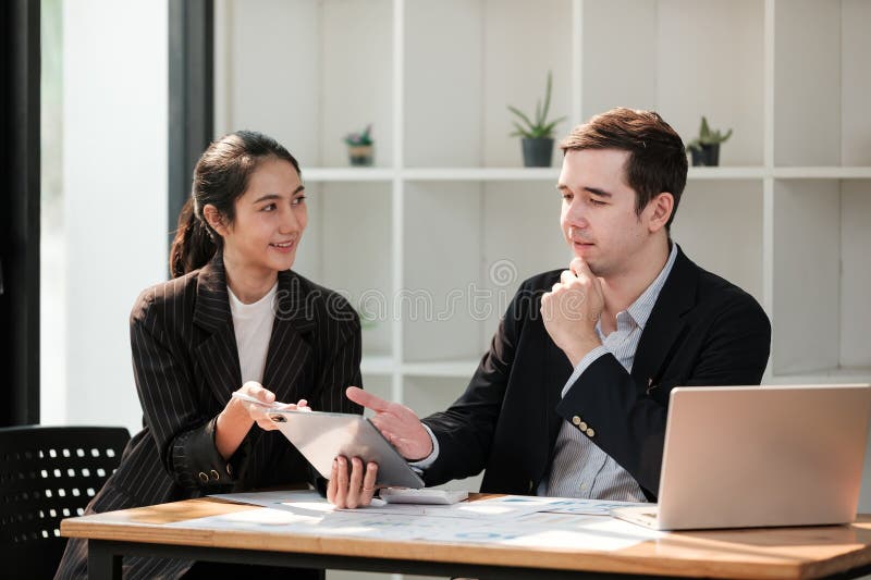 Zwei Personen sitzen an einem Schreibtisch mit Laptop und Tablet stockfoto