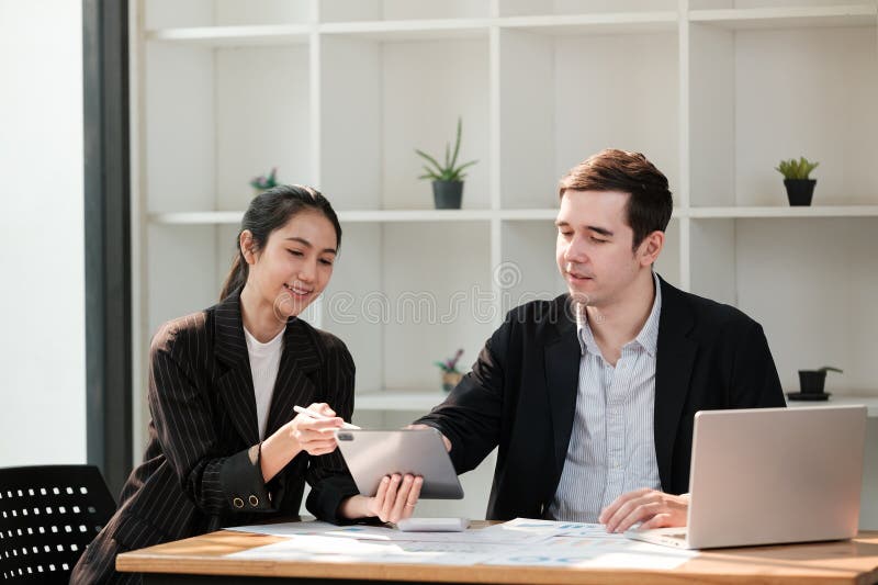 Zwei Personen sitzen an einem Tisch mit einem Laptop und einem Tablet lizenzfreie stockfotografie