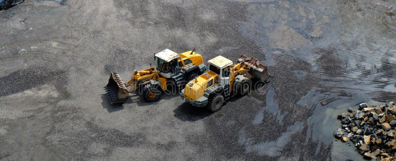 Zwei Radladerfahrzeuge mit den vorderen Eimern, die, kreuzend in den entgegengesetzten Richtungen während der Erdbewegenden Arbei lizenzfreie stockfotografie Zwei Radladerfahrzeuge mit den vorderen Eimern, die, kreuzend in den entgegengesetzten Richtungen während der Erdbewegenden Arbei lizenzfreie stockfotografie