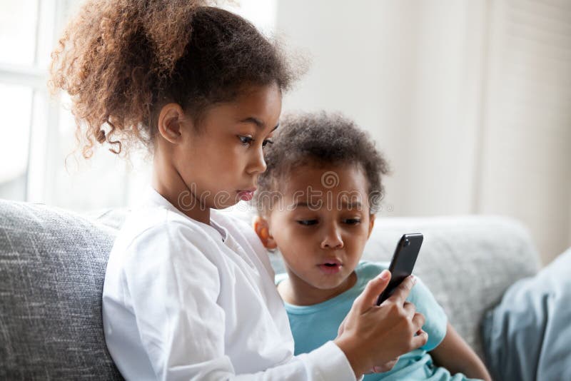 Zwei schwarze Kinder mit Handy zuhause lizenzfreie stockfotos