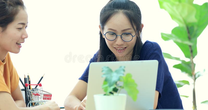 Zwei schöne asiatische Geschäftsfrauen arbeiten in einem Licht und in einem modernen Büro