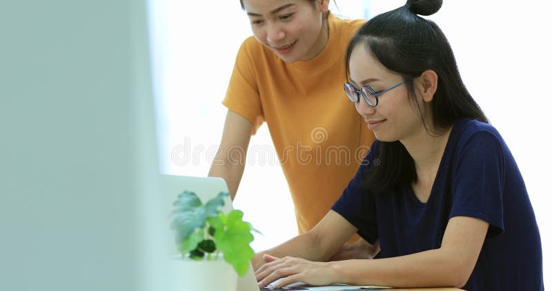 Zwei schöne asiatische Geschäftsfrauen arbeiten in einem Licht und in einem modernen Büro