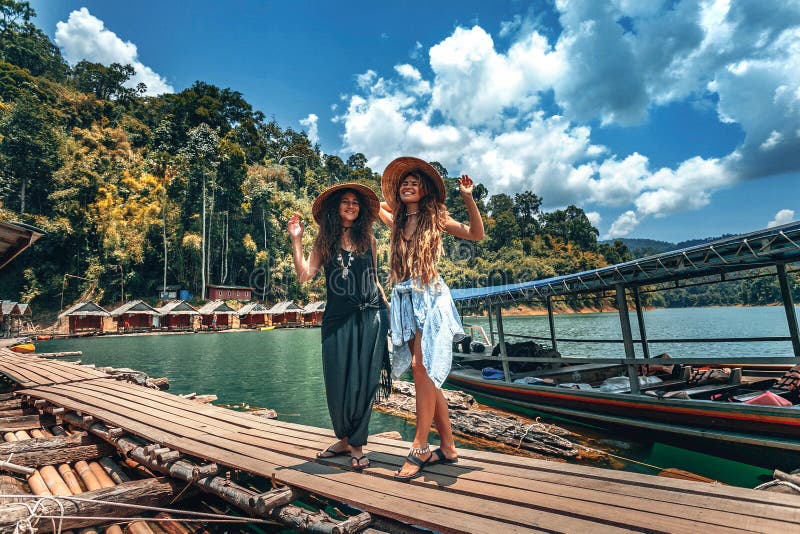 Zwei schöne, fröhliche Mädchen mit vietnamesischem Hut auf tropischem Hintergrund