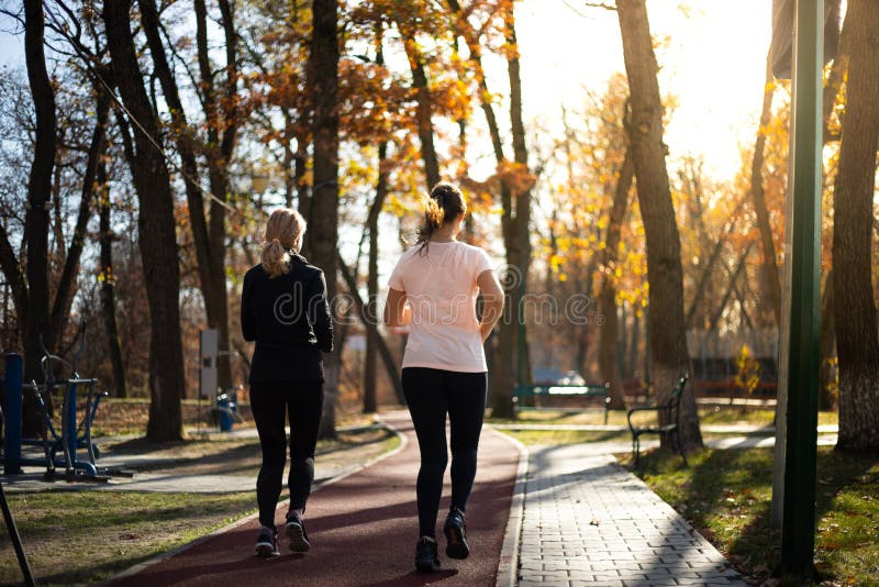 Zwei schöne geeignete Frauen, die in Parks während des Falles und der Sonnen laufen stockfotografie Zwei schöne geeignete Frauen, die in Parks während des Falles und der Sonnen laufen stockfotografie
