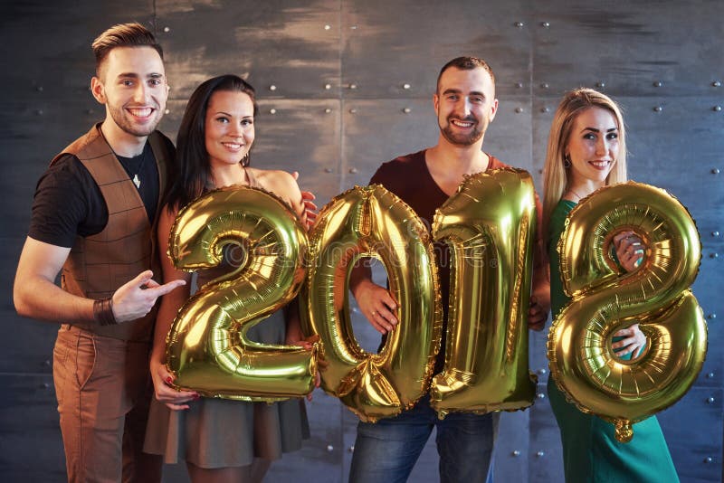 Zwei schöne junge Paare, die Spaß an neues Jahr ` s Eve Party, Pappe halten haben, nummeriert 2018 lizenzfreie stockbilder Zwei schöne junge Paare, die Spaß an neues Jahr ` s Eve Party, Pappe halten haben, nummeriert 2018 lizenzfreie stockbilder