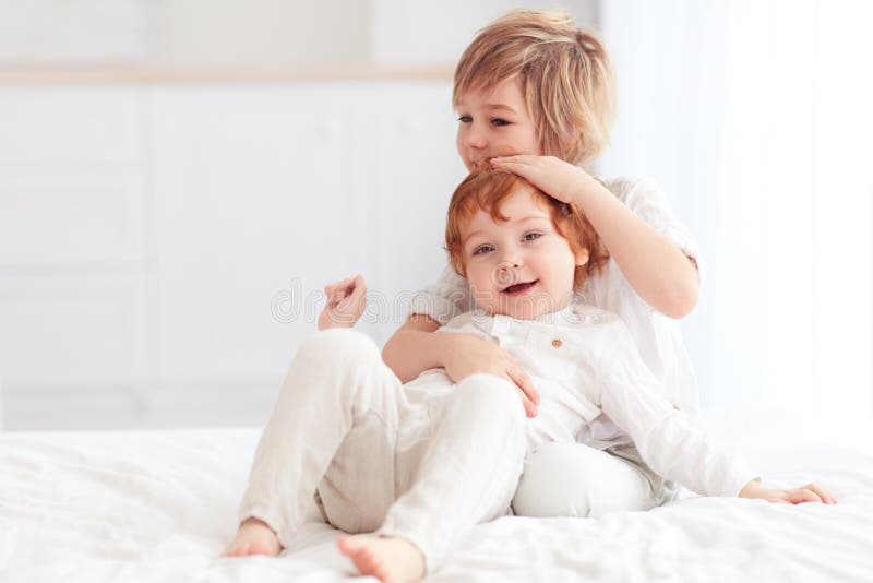 Zwei schöne Kinder, Bruderumarmung, zusammen zu Hause spielend lizenzfreies stockbild