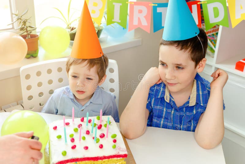 Zwei schöne Kinderjungen, die an der Geburtstagsfeier lächeln. Geburtstagskuchen lizenzfreie stockfotografie