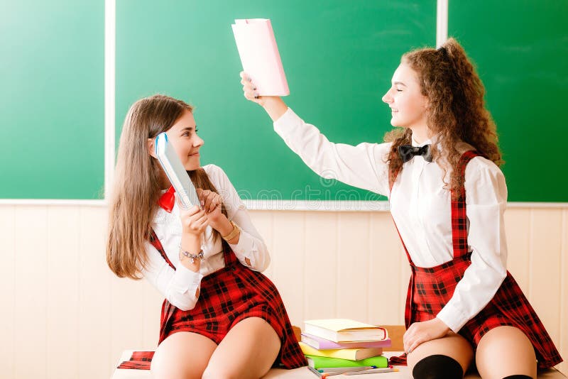 Zwei Schöne Schulmädchen Sitzen Am Schreibtisch Mit Büchern Im Klassenzimmer Stockfoto Bild