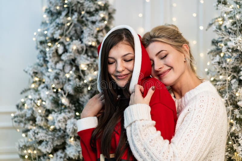 Zwei schöne Schwestern in den Strickjacken, die nahe dem Weihnachtsbaum umarmen stockfoto Zwei schöne Schwestern in den Strickjacken, die nahe dem Weihnachtsbaum umarmen stockfoto