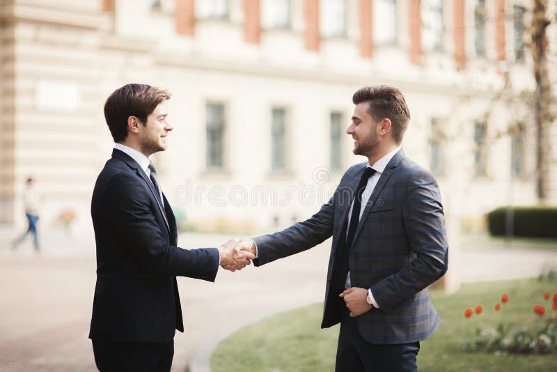 Zwei stilvolle Geschäftsmänner, die Hände in den Klagen rütteln lizenzfreie stockfotografie Zwei stilvolle Geschäftsmänner, die Hände in den Klagen rütteln lizenzfreie stockfotografie