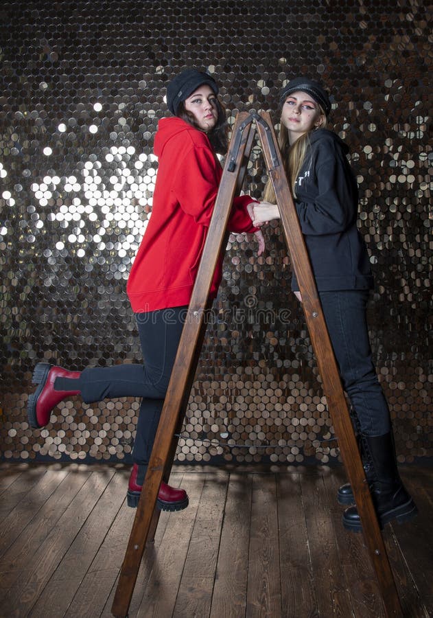 Zwei Teenagermädchen stehen auf einem Stepleiter an der goldenen Wand. lizenzfreie stockfotografie