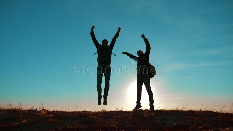 Zwei Touristen, die glückliche Glückzielleistung Natur-Landschaft springen teamwork zwei Touristenwanderermänner und -hund mit