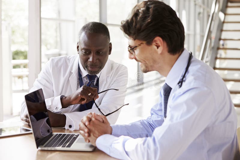 Zwei ältere Gesundheitswesenarbeitskräfte in der Beratung unter Verwendung des Laptops stockfotos Zwei ältere Gesundheitswesenarbeitskräfte in der Beratung unter Verwendung des Laptops stockfotos