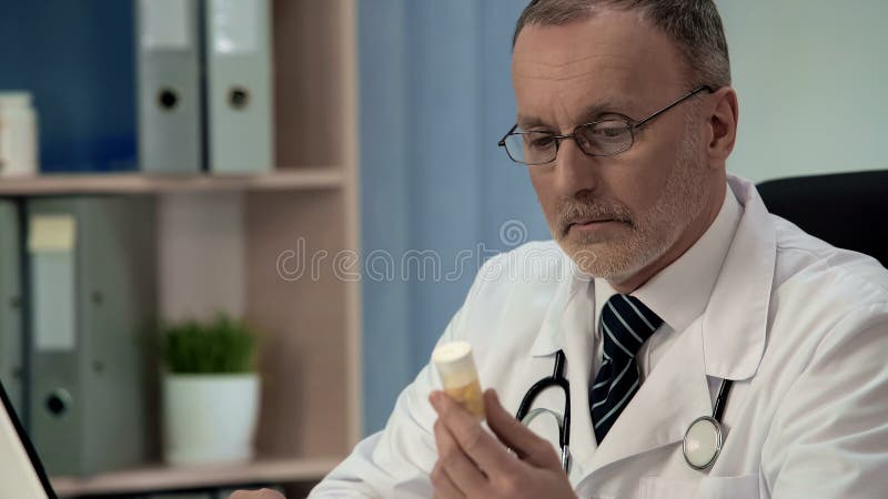 Zweifelhafter Doktor, der Pillen, gefälschte Medizin der geringen Qualität, Placebo betrachtet stockfoto Zweifelhafter Doktor, der Pillen, gefälschte Medizin der geringen Qualität, Placebo betrachtet stockfoto