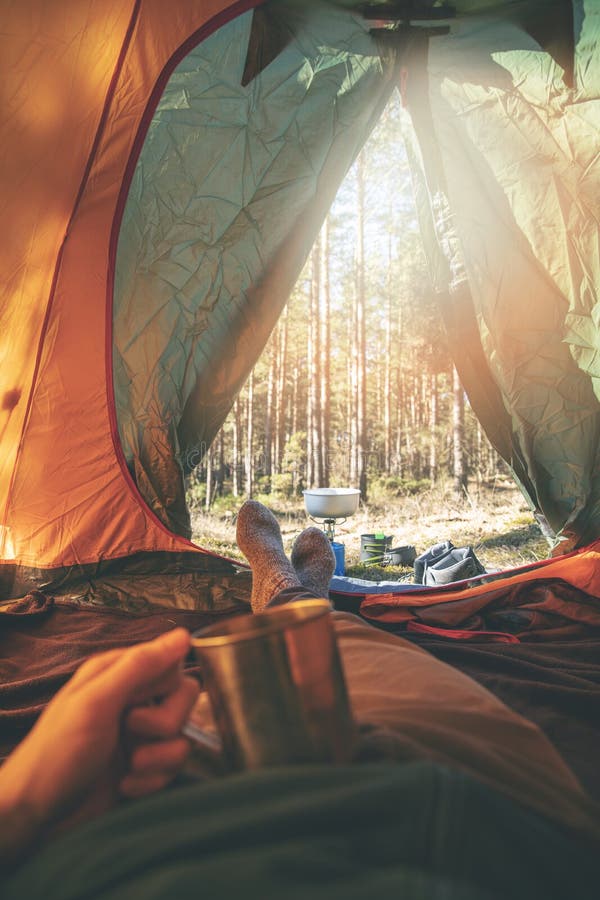 Zwerflust - mens het ontspannen in tent na stijging met kop thee stock foto Zwerflust - mens het ontspannen in tent na stijging met kop thee stock foto