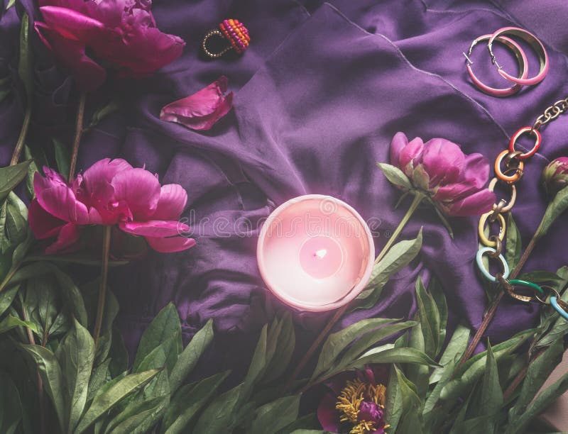 Zwerge auf violettem Stoff mit brennenden Kerzen und Schmuck. Textrahmenposition. Schönheitssalon mit Blumen stockfoto