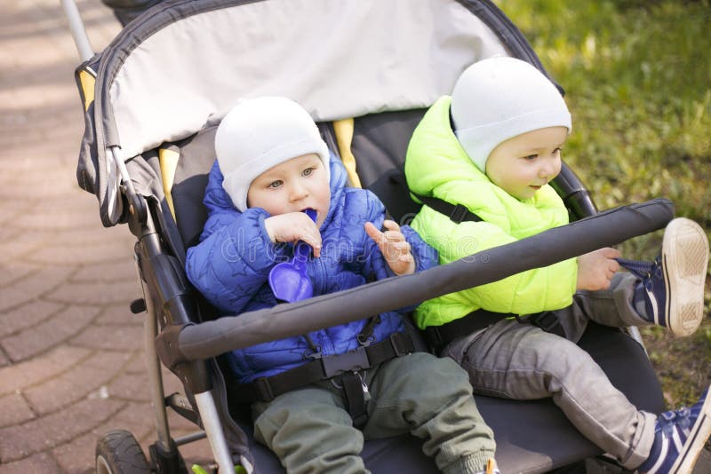 Zwillinge in einem Pram im Park stockfotografie Zwillinge in einem Pram im Park stockfotografie