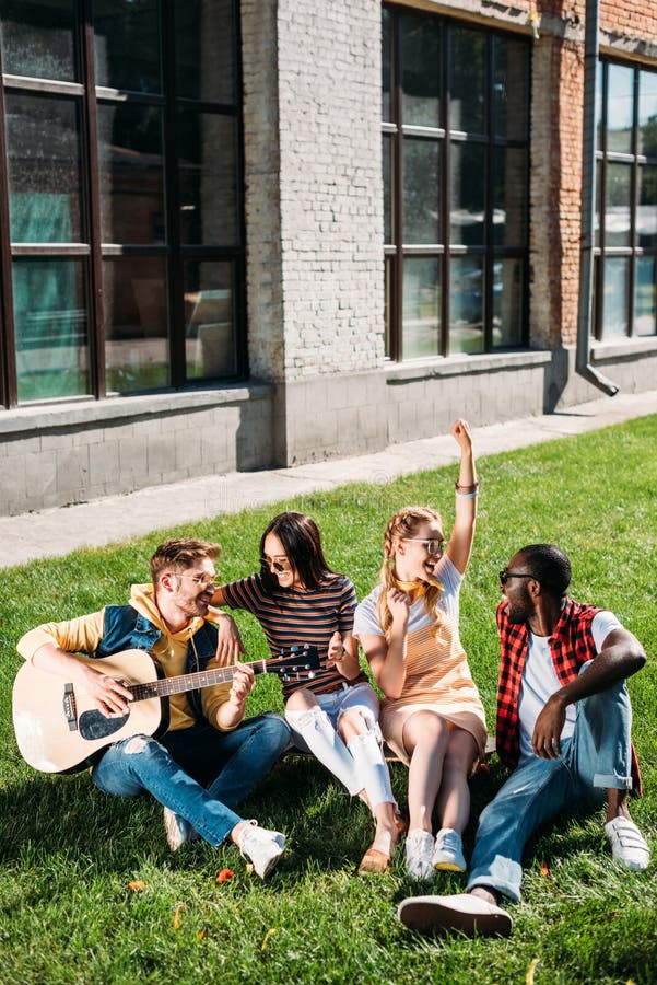zwischen verschiedenen Rassen Gruppe Freunde mit der Akustikgitarre, die auf grünem Gras stillsteht lizenzfreie stockfotos zwischen verschiedenen Rassen Gruppe Freunde mit der Akustikgitarre, die auf grünem Gras stillsteht lizenzfreie stockfotos