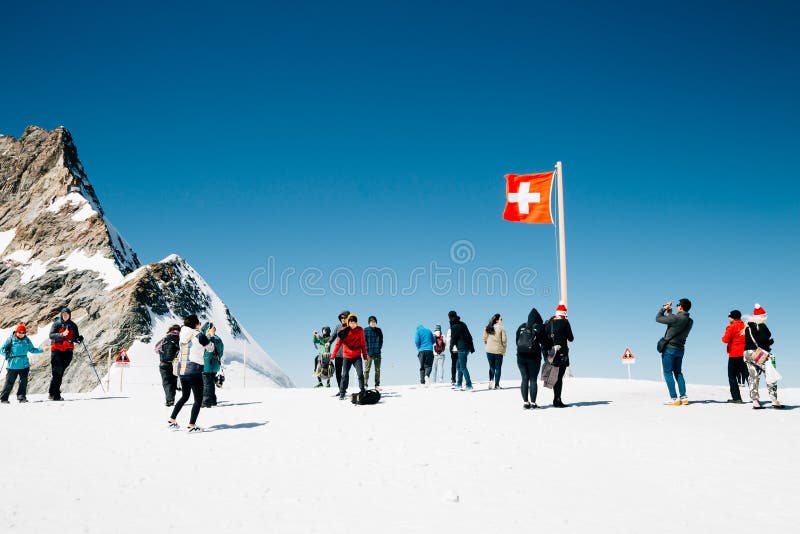Zwitserse vlag en toeristenmensen op sneeuw de bergtop van Jungfrau stock afbeelding Zwitserse vlag en toeristenmensen op sneeuw de bergtop van Jungfrau stock afbeelding