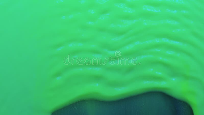 Zwolniony ruch. piękne fale zielonej farby fluorescencyjnej. wiatr rozwiewa zieloną farbę