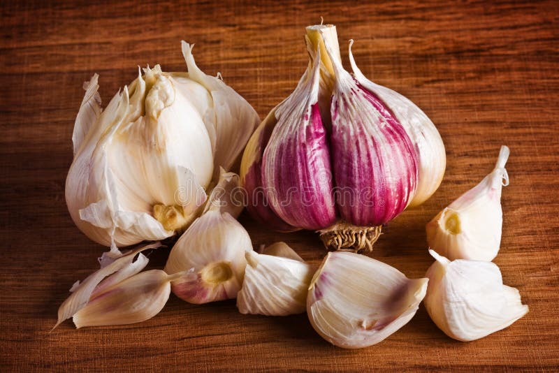 Garlic heads and cloves on wood cutting board. Garlic heads and cloves on wood cutting board.